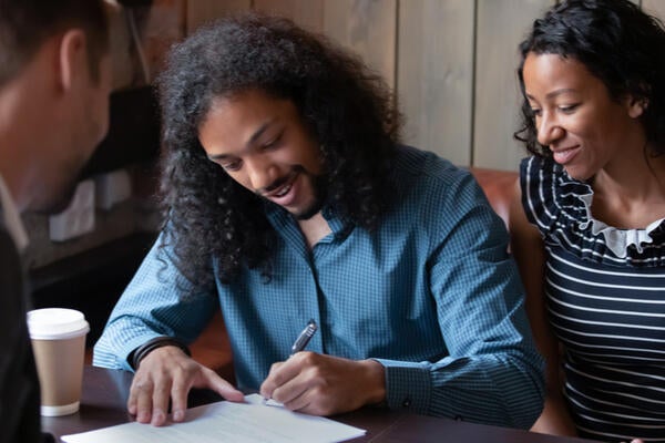 Couple signing paperwork with real estate agent