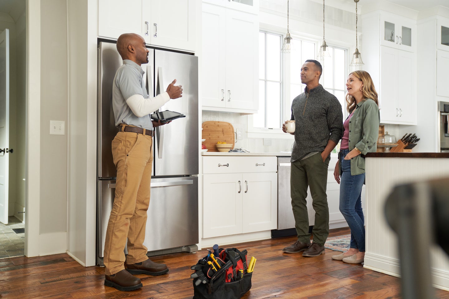 Repairman reviews refrigerator repairs with Baltimore couple.