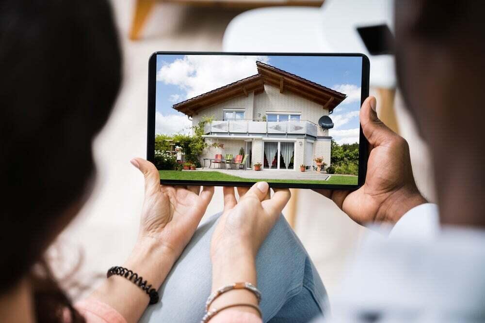  People holding a tablet displaying an image of a house.